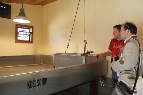 Allagash brewmaster Jason Perkins (red shirt) shows the Koelschip room to Cornelius Faus,t founder of Faust Brewing of Miltenberg, Germany.