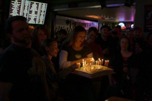 APEX owner Jesse McCann and others look on as Jana Daisy-Ensign brings out the birthday cake for Chris and Tim