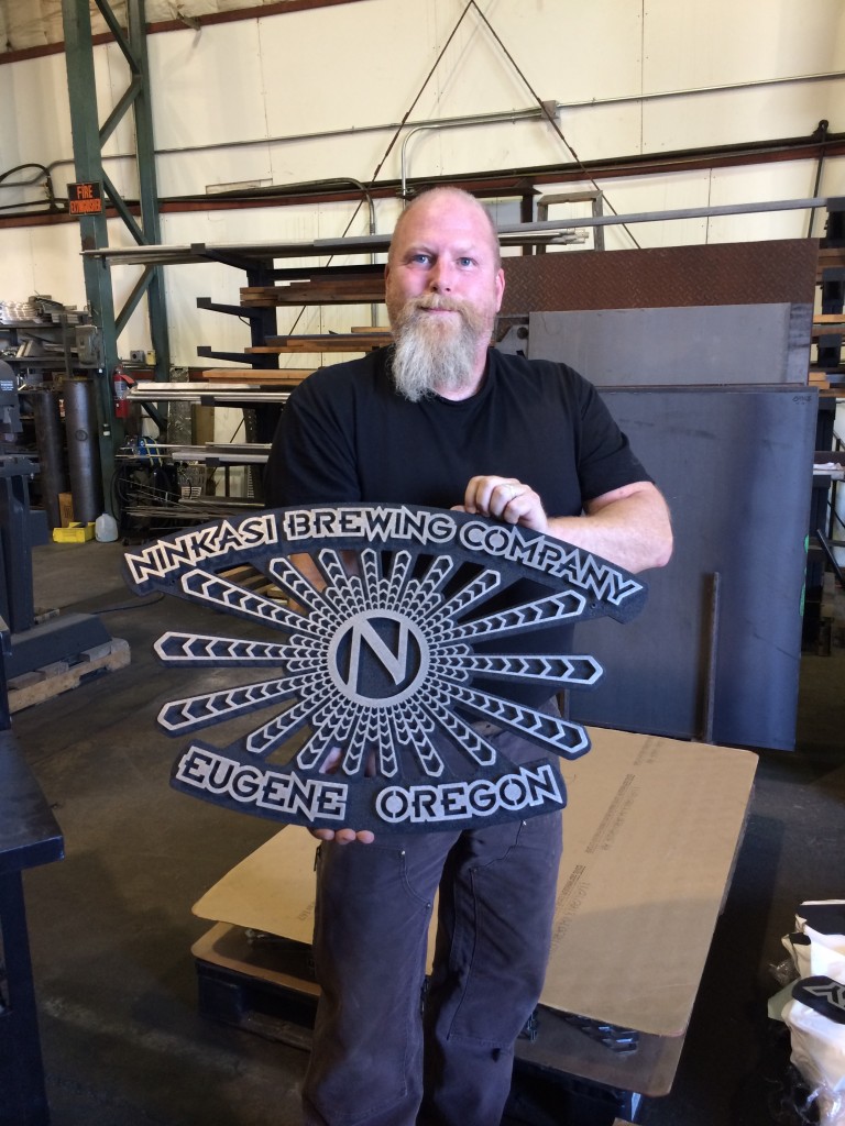 Pat "Phatty Fab" Evans holds up new Ninkasi Brewing signage from its Metal Shop
