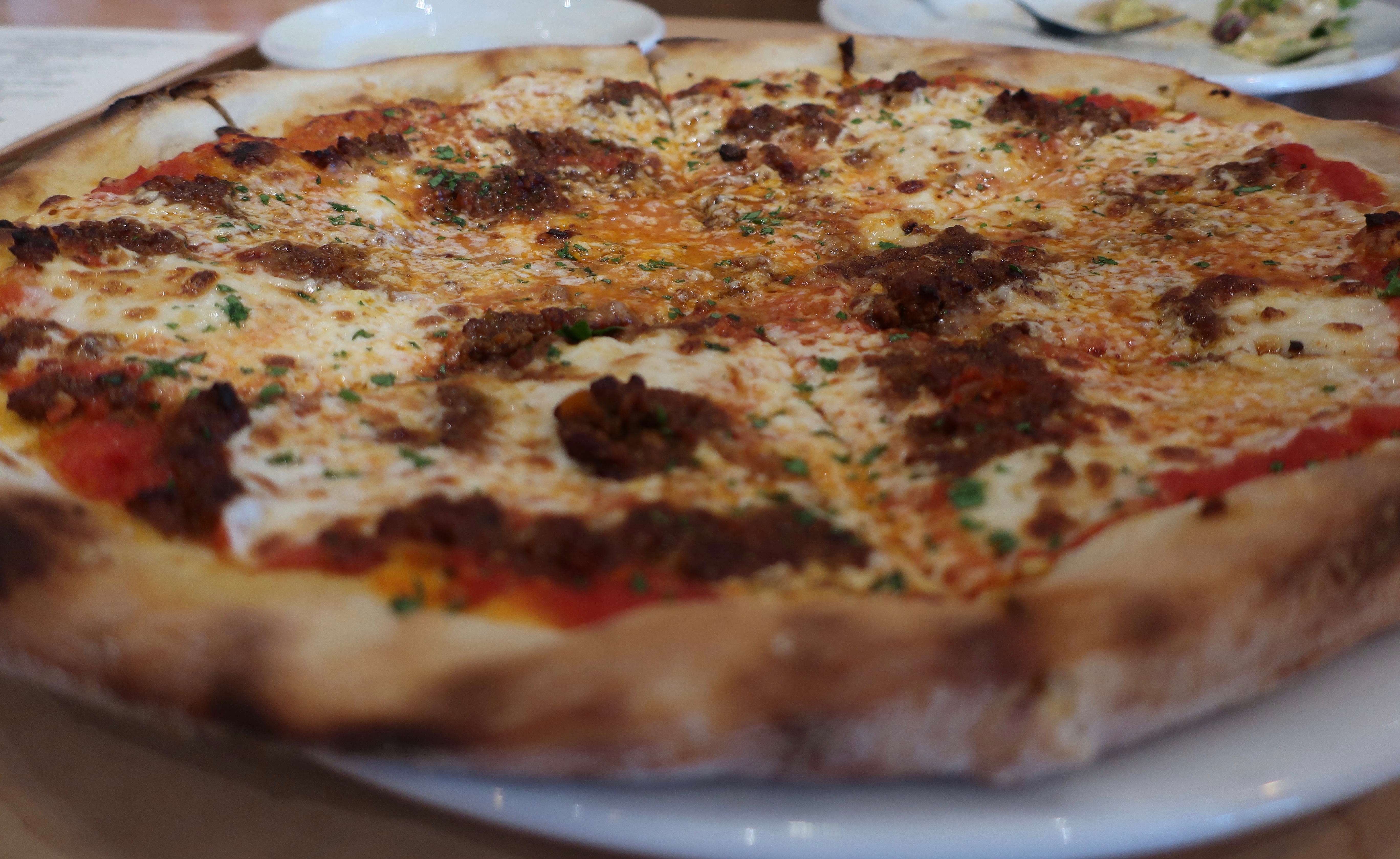 The Bolognese, one of Rally Pizza's delicious pizzas that features tomato sauce, smoky bechamel, slow-cooked beef and pork meat sauce, hand pulled mozzarella, Parmigiano-Reggiano.
