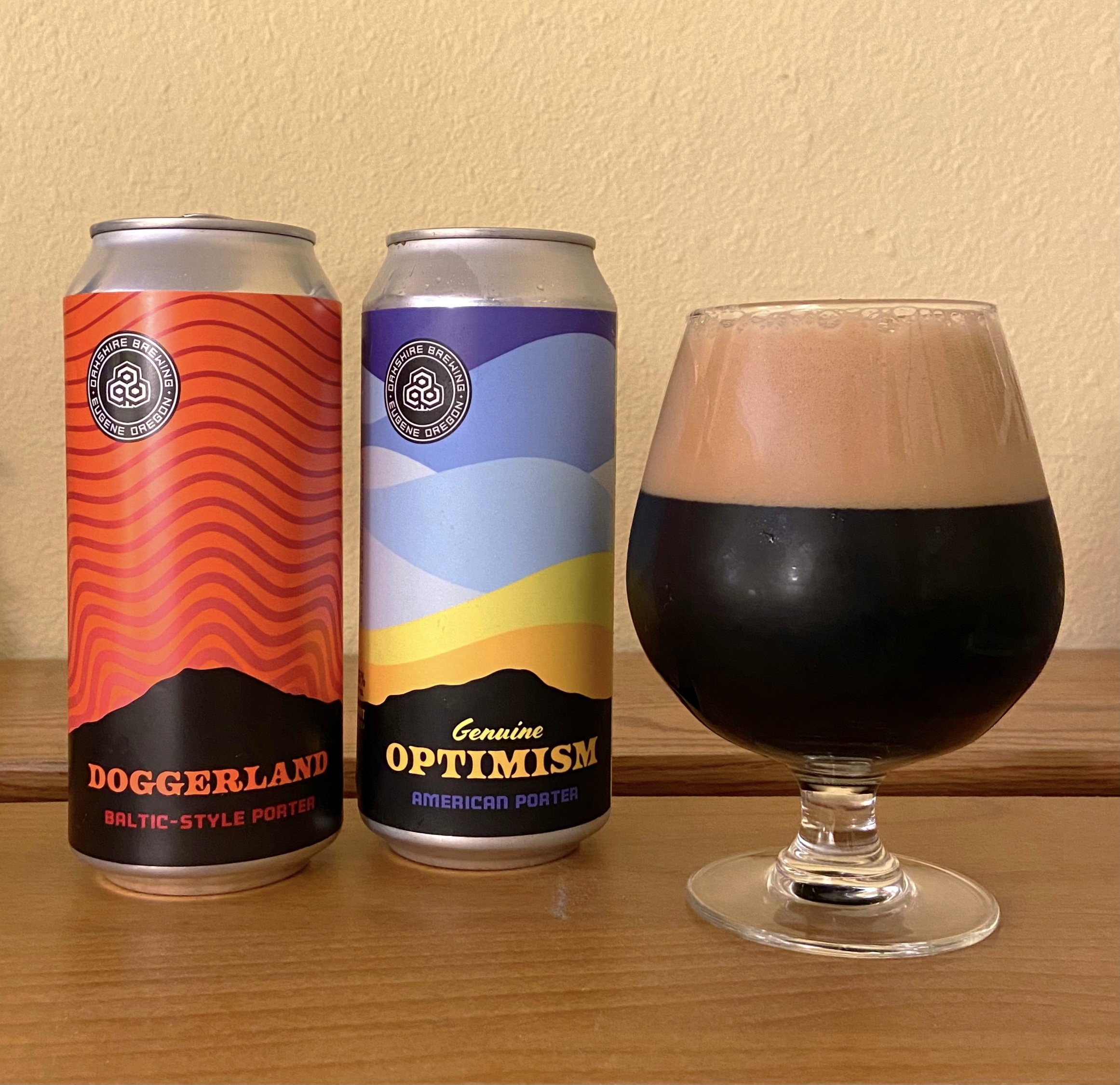 A glass pour of Genuine Optimism American Porter from Oakshire Brewing pictures alongside Doggerland Baltic-Style Porter