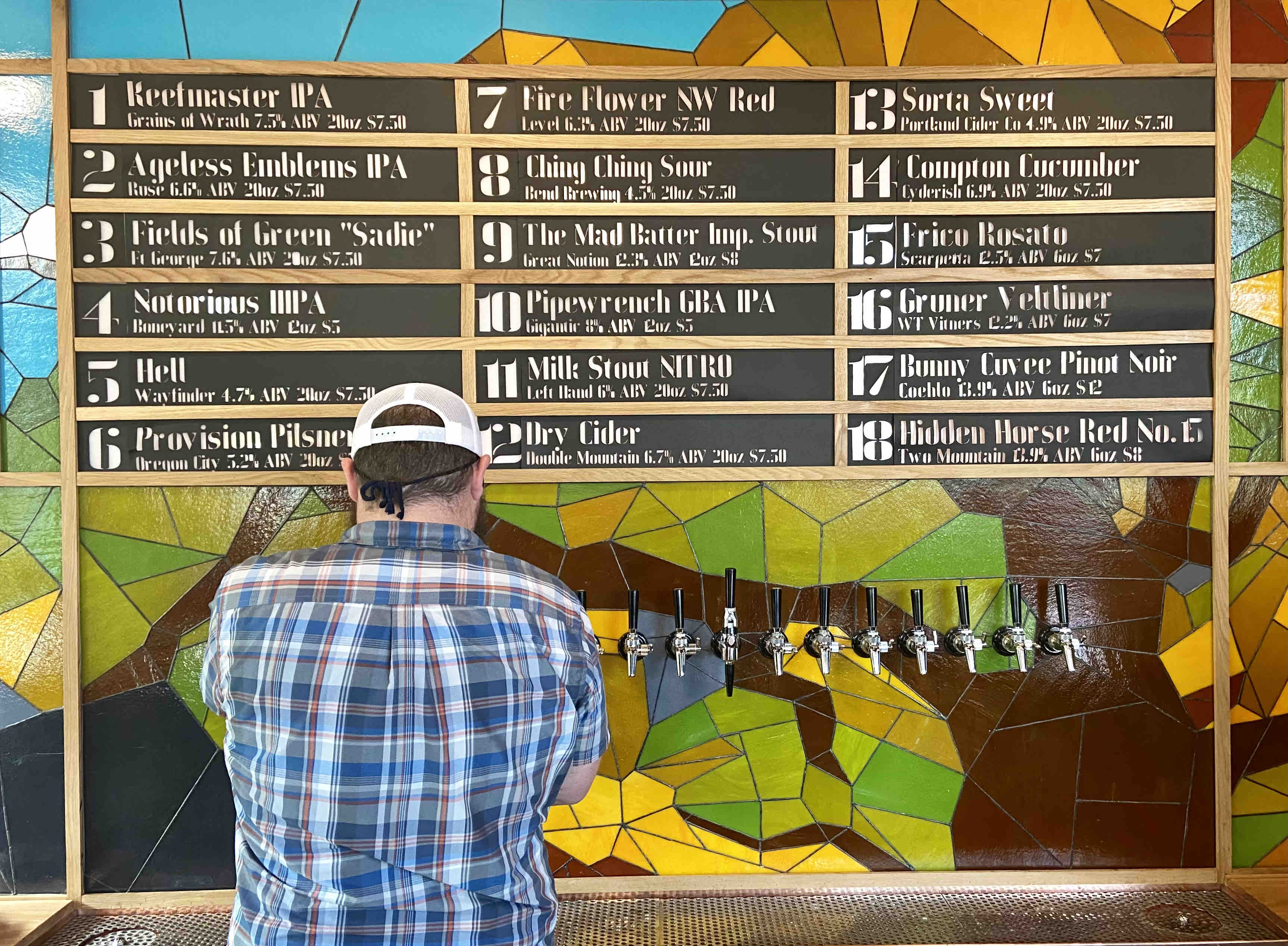 The taplist with a stained glass mosaic print adorns the backdrop of the bar at Proper Pint Oakroom.