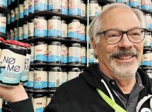 Larry SIdor holds a 6-pack of NØ MØ Hazy IPA. (image courtesy of Crux Fermentation Project)