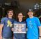 Reuben's Brews celebrates 10 years on Saturday, August 6, 2022. Reuben's Brews co-founders Mike Pfeiffer, Grace Robbings, and Adam Robbings holding a photo of themselves from the grand opening of Reuben's Brews in August of 2012. (image courtesy of Reuben's Brews)