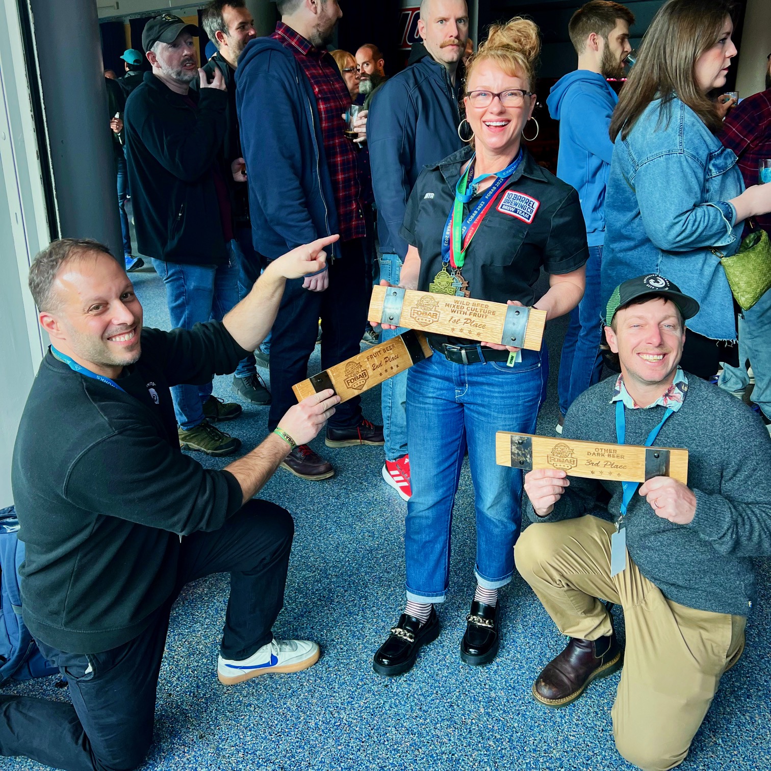 Ben Edmunds and Daniel Hynes of Breakside Brewery having fun while bowing down to Tonya Cornett on her trio of medals at the 2023 Festival of Wood and Barrel Aged Beer.