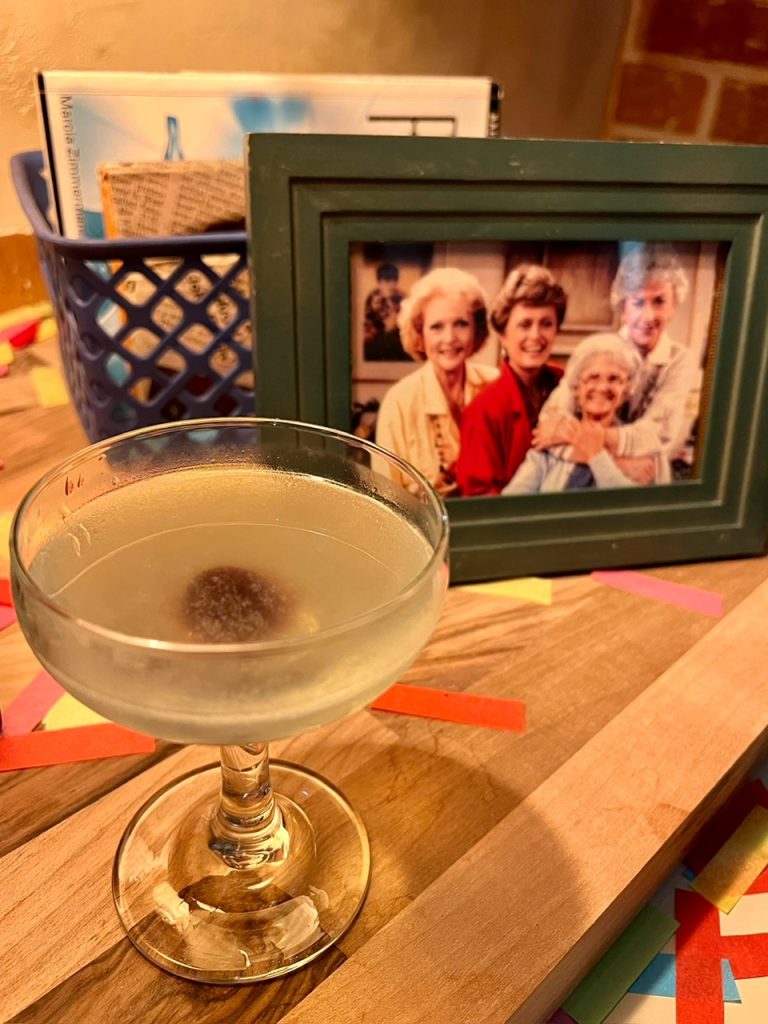 A mini Aviation Cocktail with a picture of the Golden Girls inside Wade Wilson's apartment at Aviation American Gin.