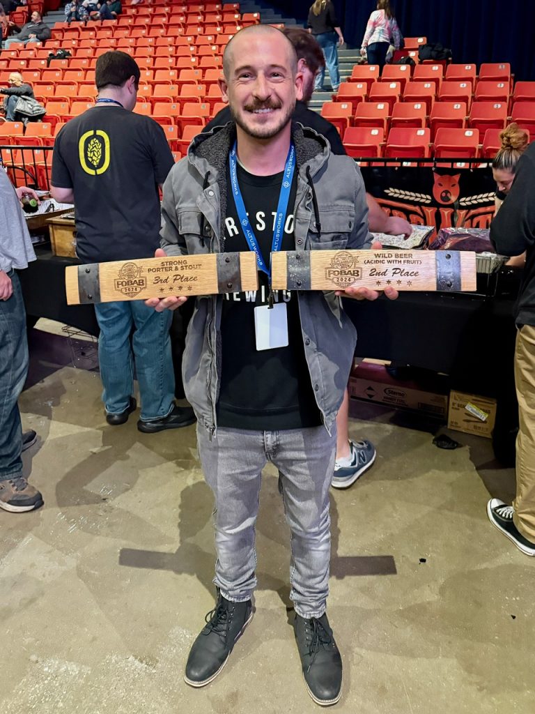 Jordan Ziegler of Firestone Walker Brewing displaying the brewery's two awards from the 2024 Festival of Wood & Barrel Aged Beer.